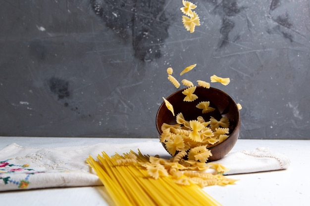 A front view raw italian pasta long and little pasta bowl