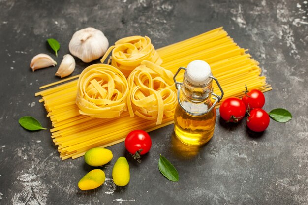 Front view raw italian pasta with garlic and tomatoes on light-grey cuisine meal color food