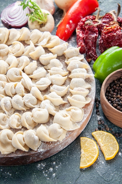 Front view raw little dumplings with flour and vegetables on dark surface