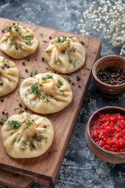 Free Photo front view raw little dumplings with tomato sauce and seasonings on a gray surface meat dough meal cake cooking dish cuisine dinner