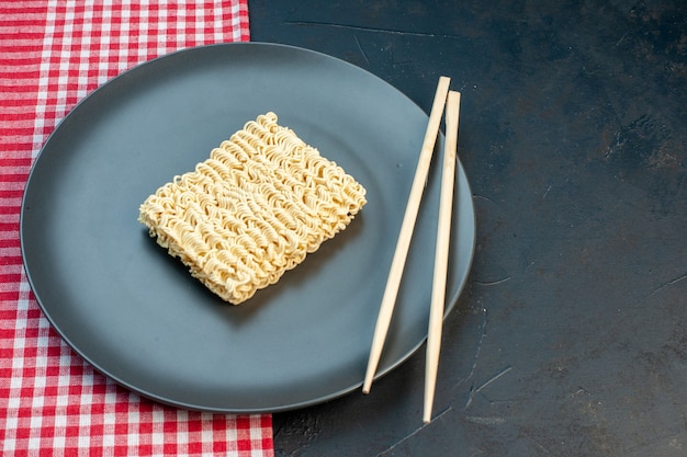 Front view raw noodles inside plate with sticks on dark table