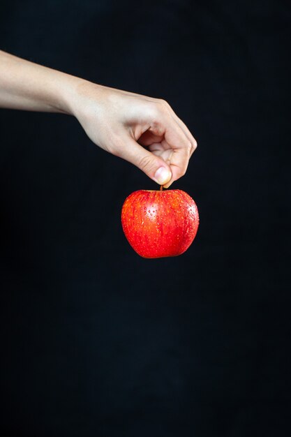 Front view red apple in hand on dark surface