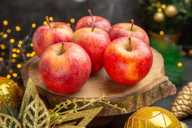 Front view red apples around christmas toys on dark background