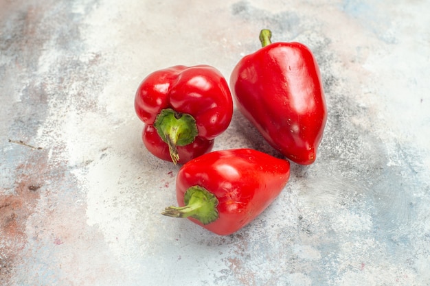 Front view red bell peppers on nude background free space