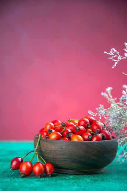 Front view red berries inside plate on green-pink desk berry wild fruit health  color