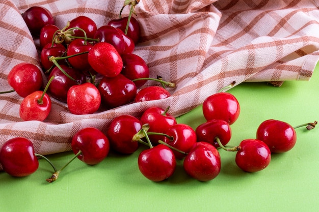 Front view red cherry with a kitchen towel on light green