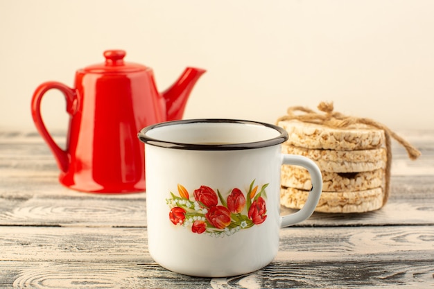 Free photo a front view red kettle with cup of coffee and crackers on the grey rustic table drink coffee color