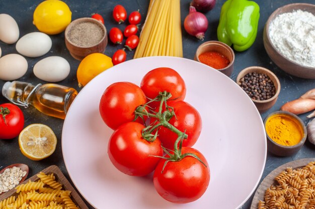 Front view red tomatoes with raw pasta vegetables seasonings ands on dark 