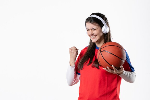 Front view rejoicing young female in sport clothes with basketball