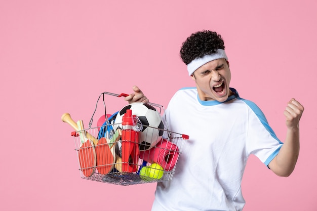 Free photo front view rejoicing young male in sport clothes with basket full of sport things