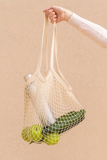 Front view reusable bag with food held by woman hand