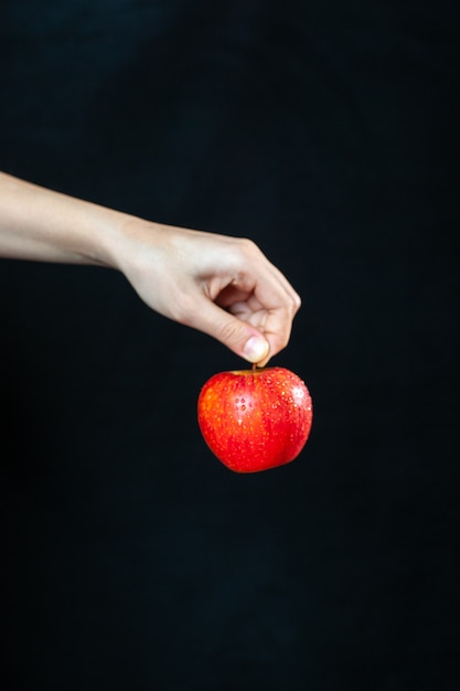 Front view ripe red apple in hand on dark surface