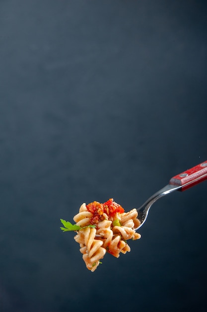 Free photo front view rotini pasta on fork on dark isolated surface with free space