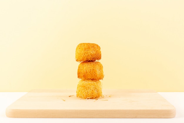 Free photo a front view round delicious cakes sweet tasty round formed bakes isolated on the cream colored background sweet sugar confectionery