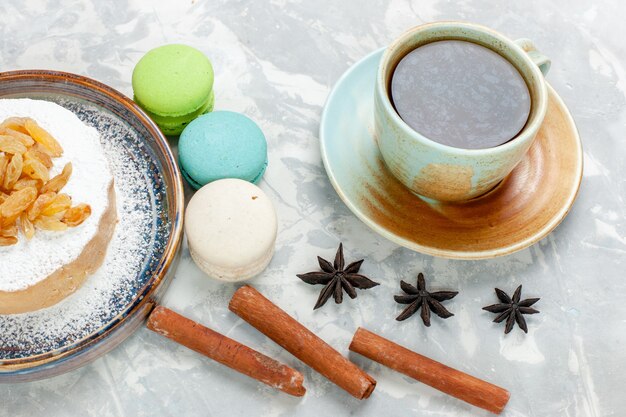 Free Photo front view round little cake sugar powdered with raisins tea and french macarons on white desk sugar sweet biscuit cake cream pie