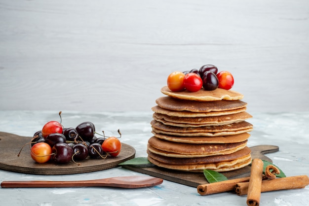 A front view round pancakes baked and delicious with cherries on the light desk cake fruit  dessert