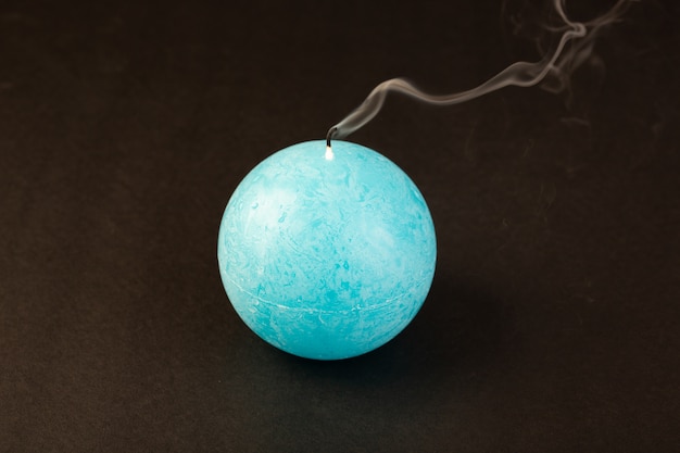 Free photo a front view round shaped candle blew out blue colored designed on the dark background bright fire decoration