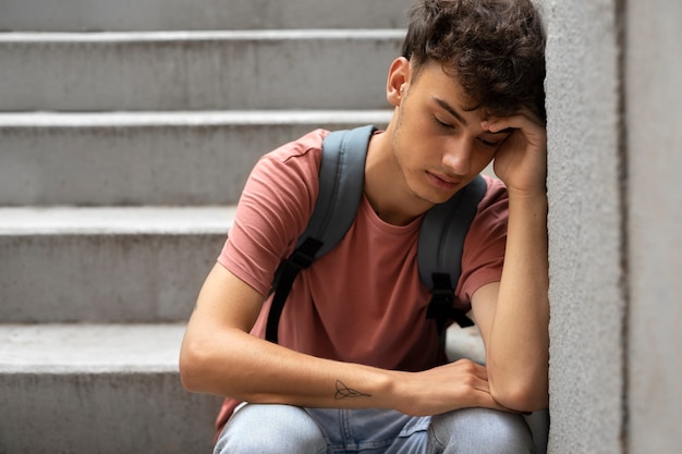 Free photo front view sad boy sitting on stairs