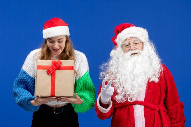 Front view of santa claus along with female who's holding present on blue wall