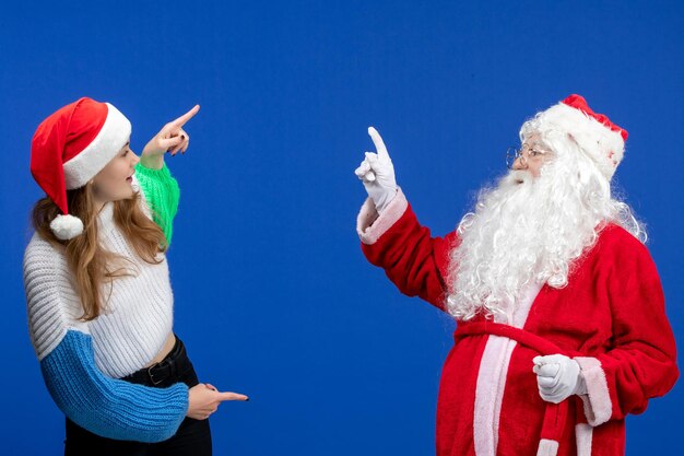 Free photo front view of santa claus along with young female just standing on blue wall