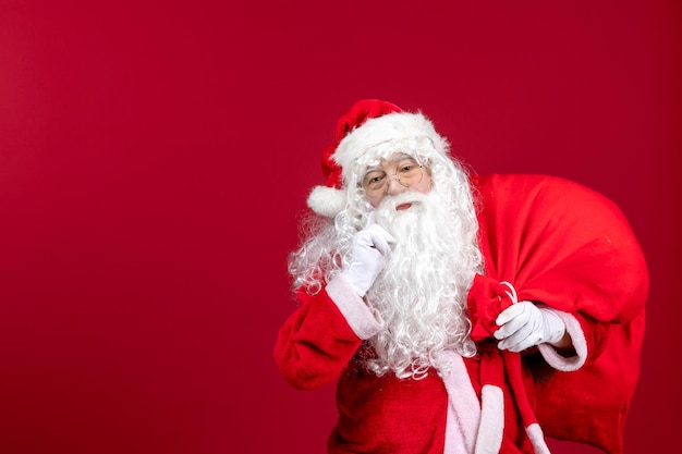 Front view santa claus carrying red bag full of presents on red emotions new year christmas holiday