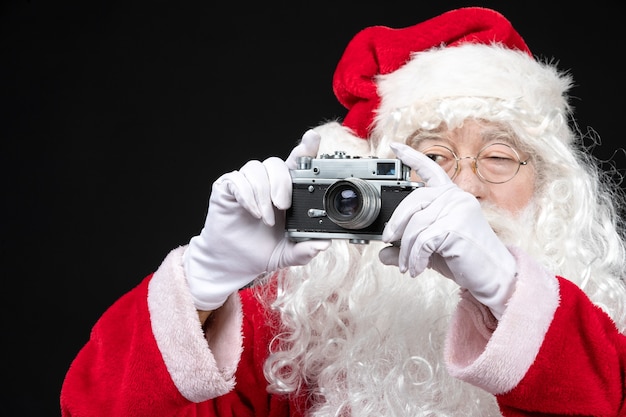 Free photo front view santa claus in classic red suit taking photo with camera