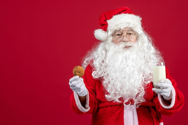 Front view santa claus eating biscuits and drinking milk