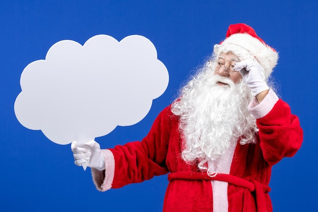 Free Photo front view santa claus holding big cloud shaped sign on the blue snow color christmas