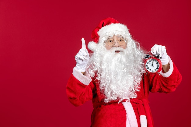 Front view santa claus holding clock on red desk xmas new year emotion