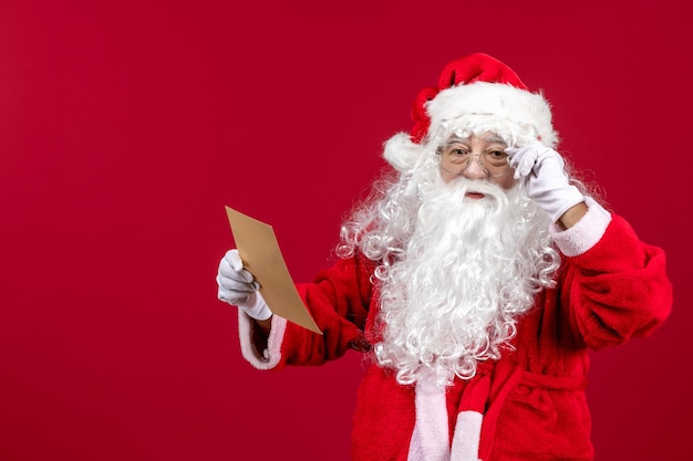 Front view santa claus reading letter from kid on red xmas holidays emotion