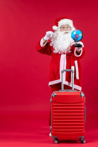 Front view of santa claus with bag preparing for trip on red wall