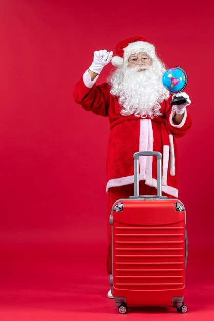 Front view of santa claus with bag preparing for trip on red wall