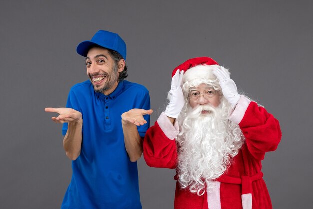 Front view of santa claus with male courier on a grey wall