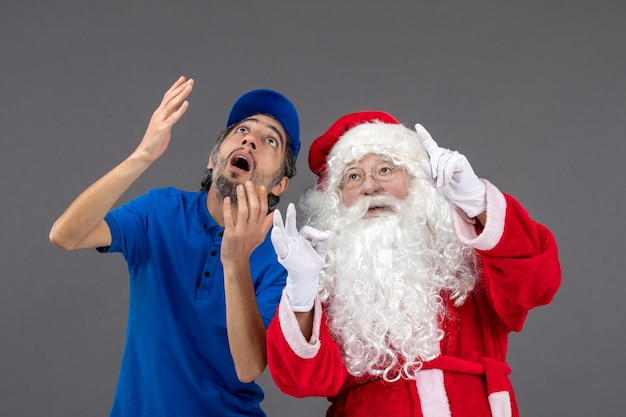 Front view of santa claus with male courier on a grey wall