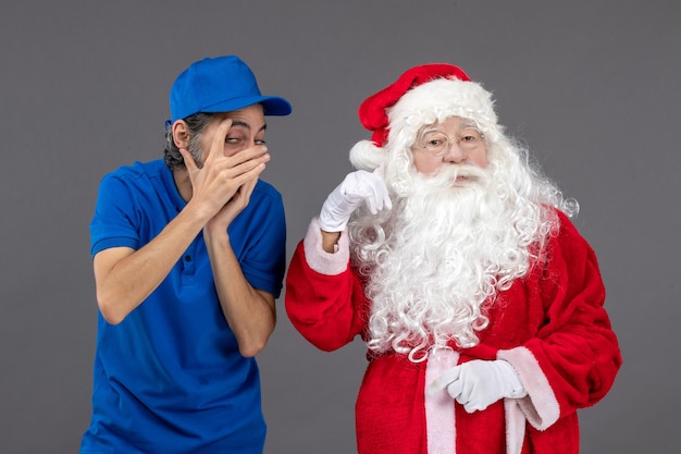 Front view of santa claus with male courier on grey wall