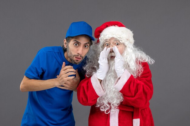 Front view of santa claus with male courier on grey wall