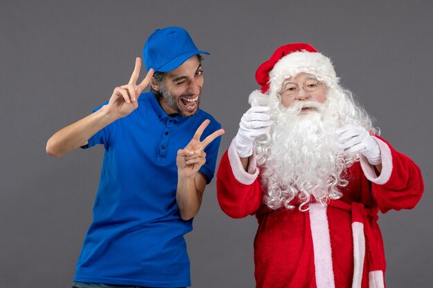 Front view of santa claus with male courier on grey wall