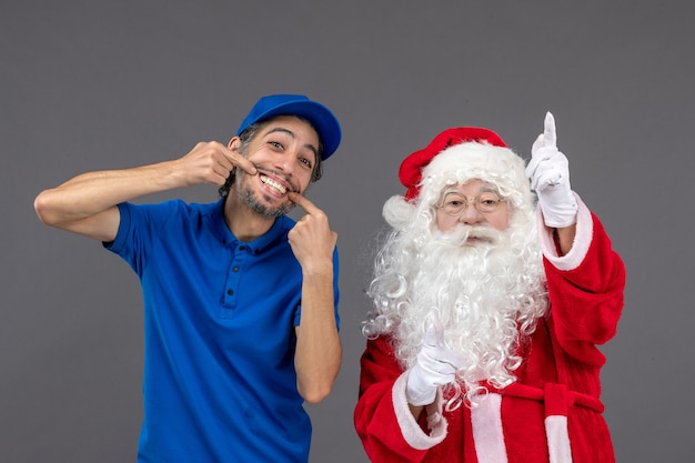 Front view of santa claus with male courier on the grey wall