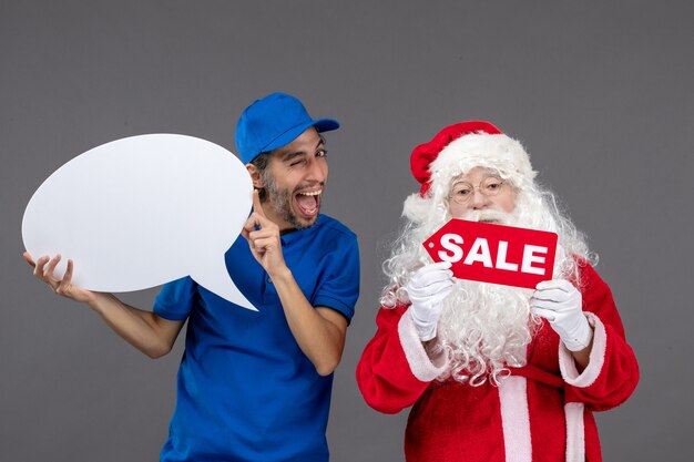 Free Photo front view of santa claus with male courier holding white sign and sale banner on grey wall