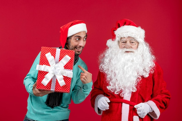 Free Photo front view santa claus with male holding holiday present on red emotion red gifts xmas new year