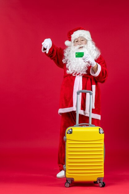 Free Photo front view of santa claus with yellow bag holding green bank card on red wall