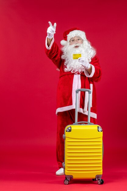 Front view of santa claus with yellow bag holding yellow bank card on red wall