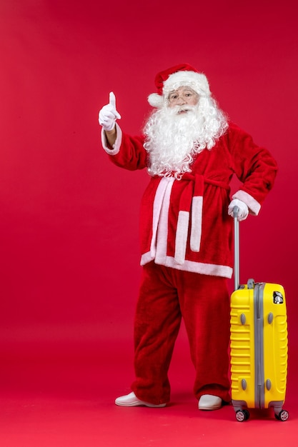 Free Photo front view of santa claus with yellow bag preparing for trip on red wall