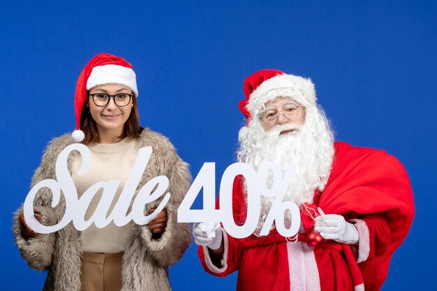 Front view santa claus with young female holding sale writings on blue holiday xmas color