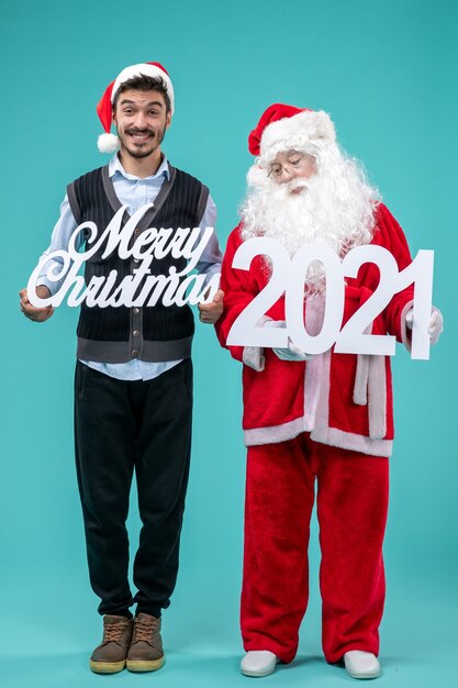 Front view santa claus with young male holding merry christmas and writings on the blue background