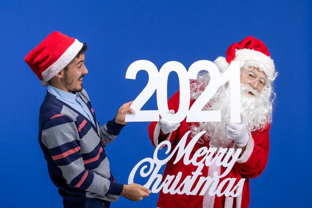 Front view santa claus with young male holding and merry christmas writings on blue new year