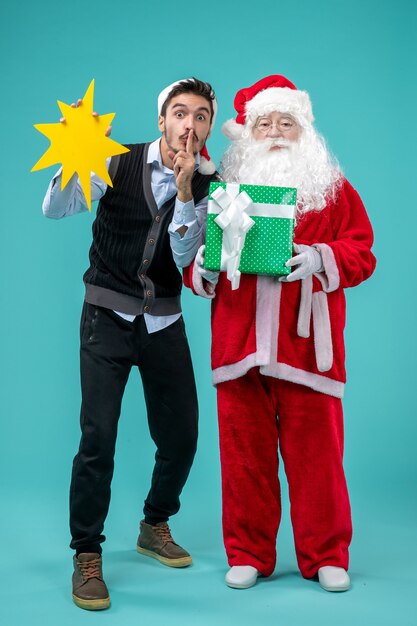 Front view santa claus with young male who's holding yellow sign on blue background