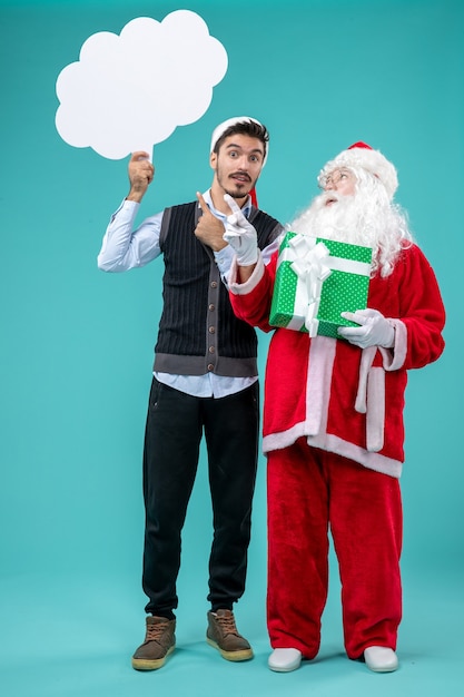 Free Photo front view santa claus with young male whos holding white cloud sign on blue background