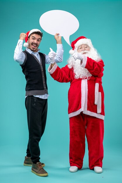 Free Photo front view santa claus with young male whos holding white sign on blue background