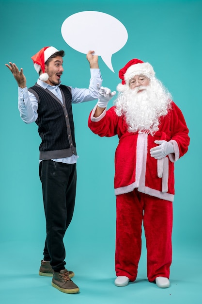 Free Photo front view santa claus with young male whos holding white sign on blue floor snow xmas new year holiday color